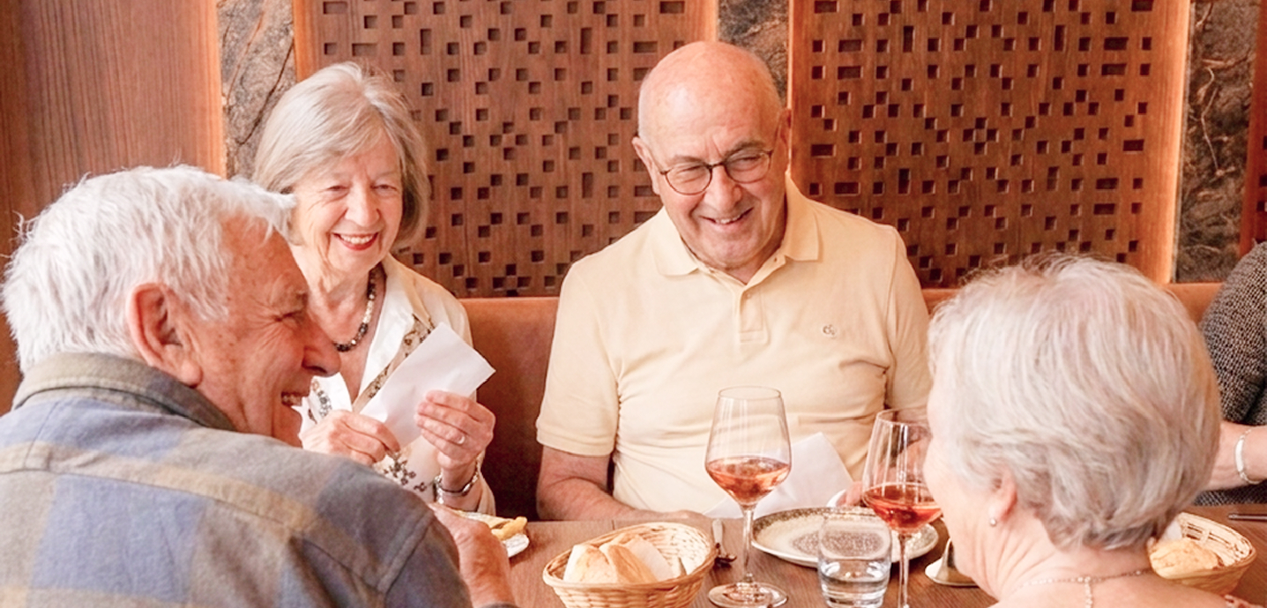 a group of friends or family enjoying a meal together at a long table with food and drinks