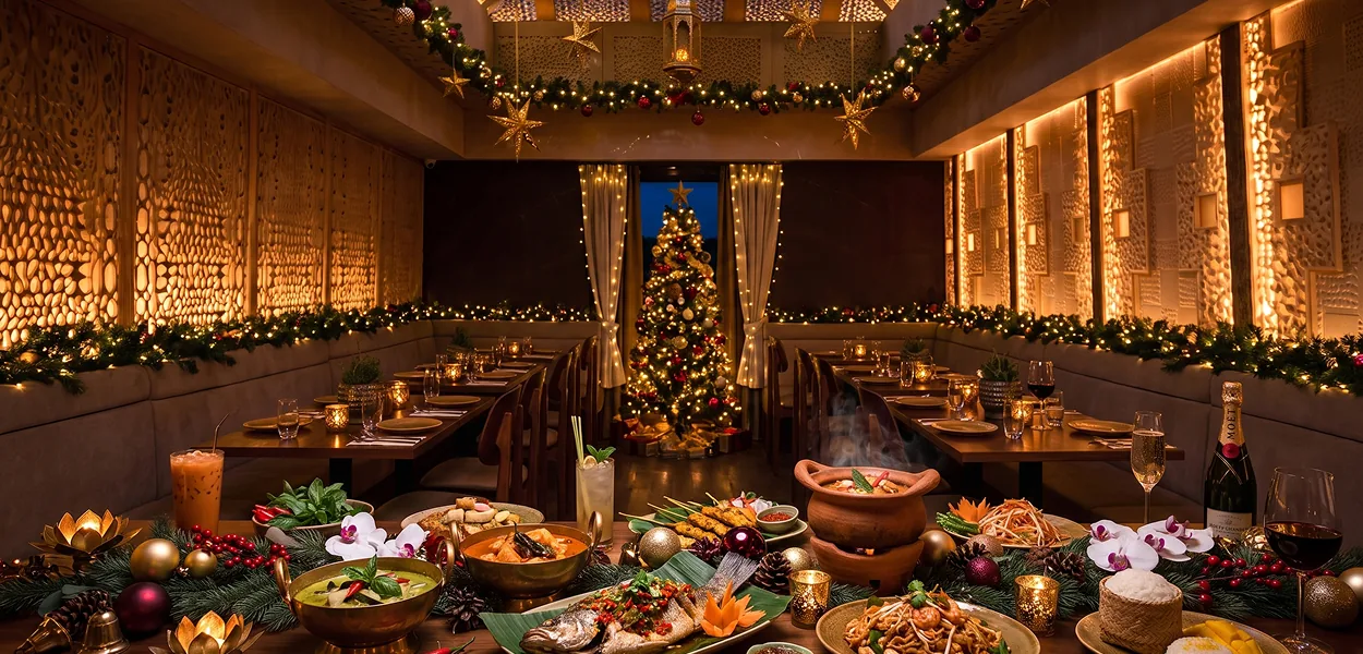 Dining room decorated for Christmas with a lit tree, garlands and a table of Thai dishes including whole fish and curry