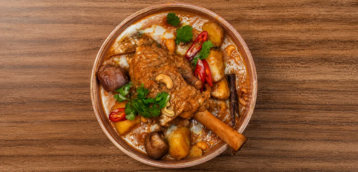 Lamb shank massaman curry with potatoes, cashew nuts, cinnamon stick and red chilli in a bowl at Nara Thai