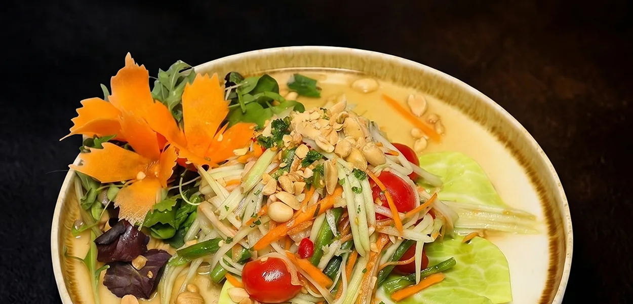 Papaya salad topped with peanuts and cherry tomatoes, with a carved flower garnish, at Nara Thai in Chiswick