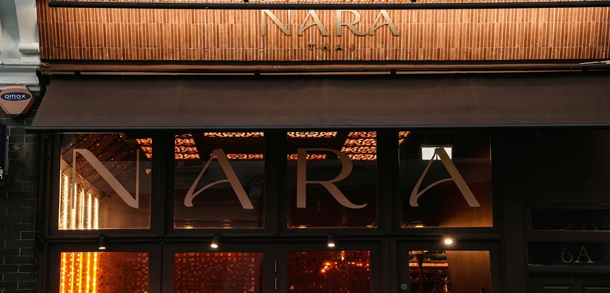 Nara Thai restaurant frontage in Chiswick with illuminated NARA THAI sign, dark awning and lettered windows