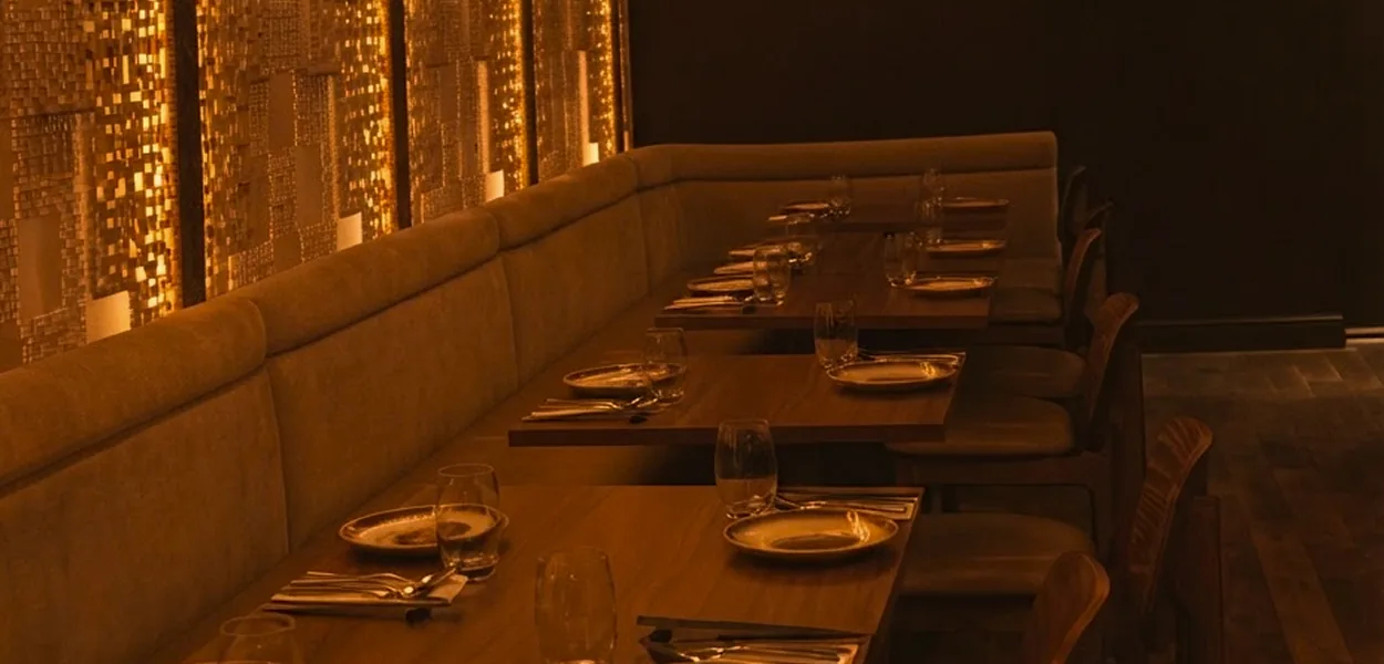 Nara Thai Chiswick dining room with laid tables, long banquette seating and softly lit gold mosaic wall panels